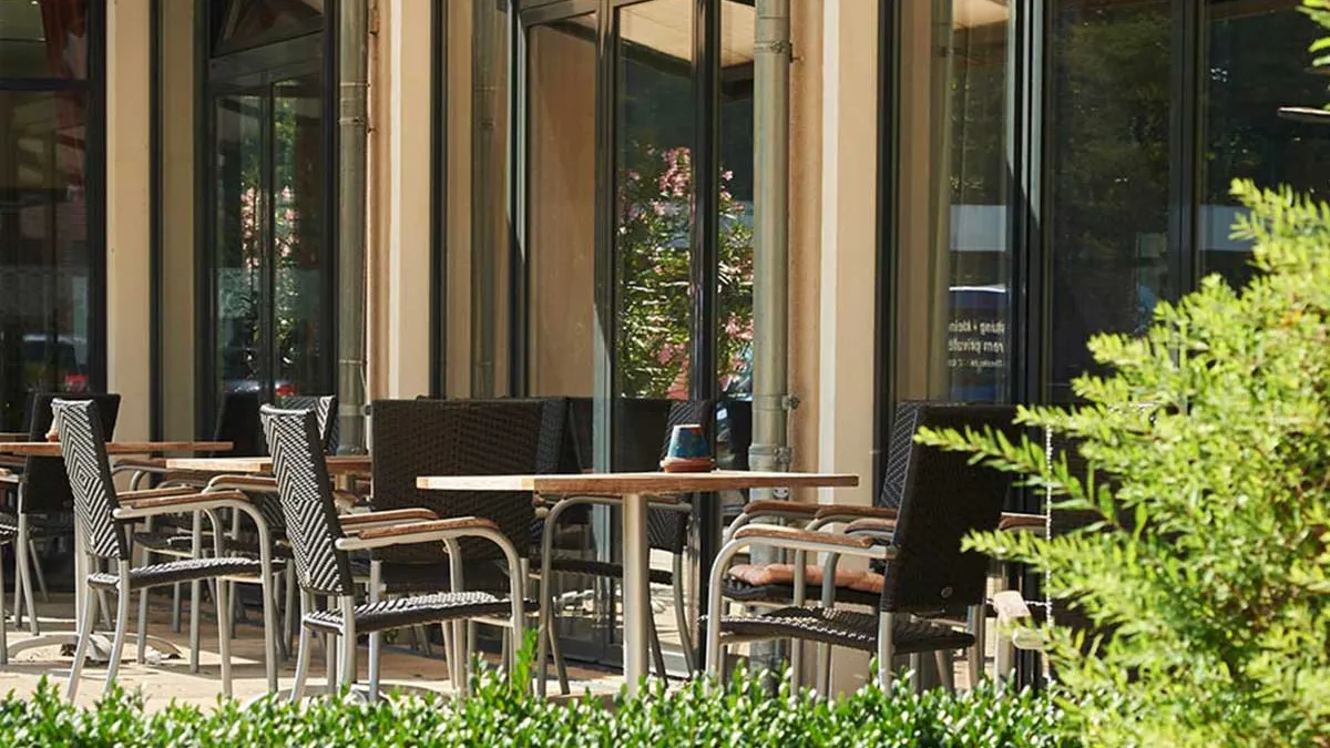 Sonnige Terrasse mit Tischen und Stühlen im PFLEGEN & WOHNEN HAMBURG Alsterberg.