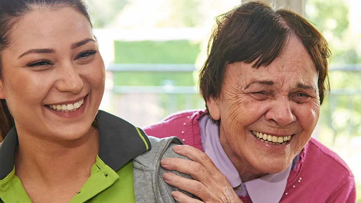 Bewohnerin des PFLEGEN & WOHNEN HAMBURG-Standorts Marienthal lacht gemeinsam mit Pflegerin.