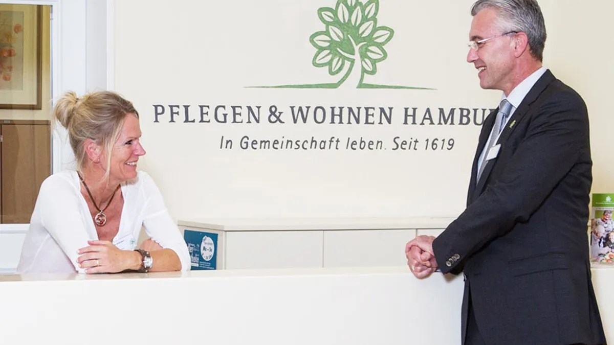 Mitarbeiter unterhalten sich an der Rezeption im PFLEGEN & WOHNEN HAMBURG Farmsen.
