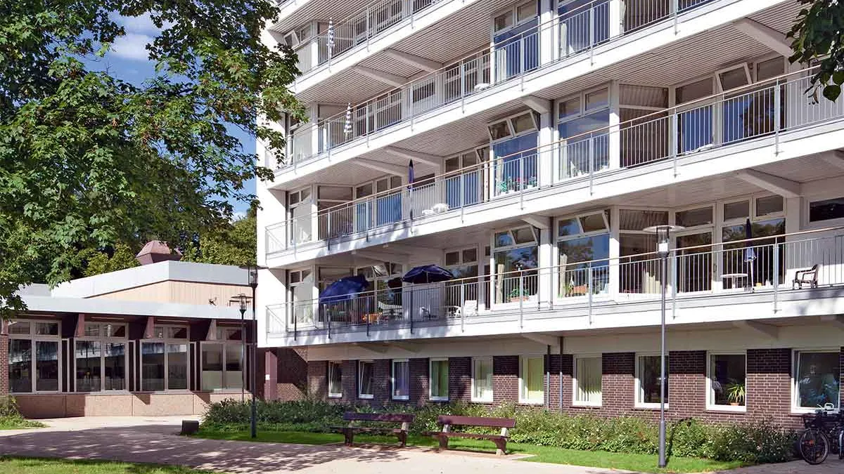 Außenansicht des Gebäudes von PFLEGEN & WOHNEN HAMBURG in Horn. Davor stehen zwei Bänke.