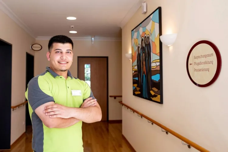 Jaid Shani Baqi, Mitarbeiter bei PFLEGEN & WOHNEN HAMBURG, auf dem Flur des Standorts Finkenau, schätzt Respekt, Empathie und Fachkompetenz in der Pflege.