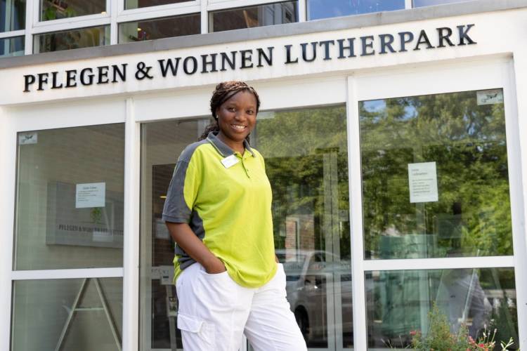 Kossia Edwige Neugart vor dem Eingang von PFLEGEN & WOHNEN HAMBURG am Standort Lutherpark, schätzt das eingespielte Team.