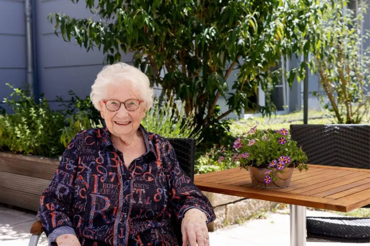Ursula Heiden im Außenbereich des Standorts Holstenhof bei PFLEGEN & WOHNEN HAMBURG, schätzt vielfältige Aktivitäten in der Pflege.