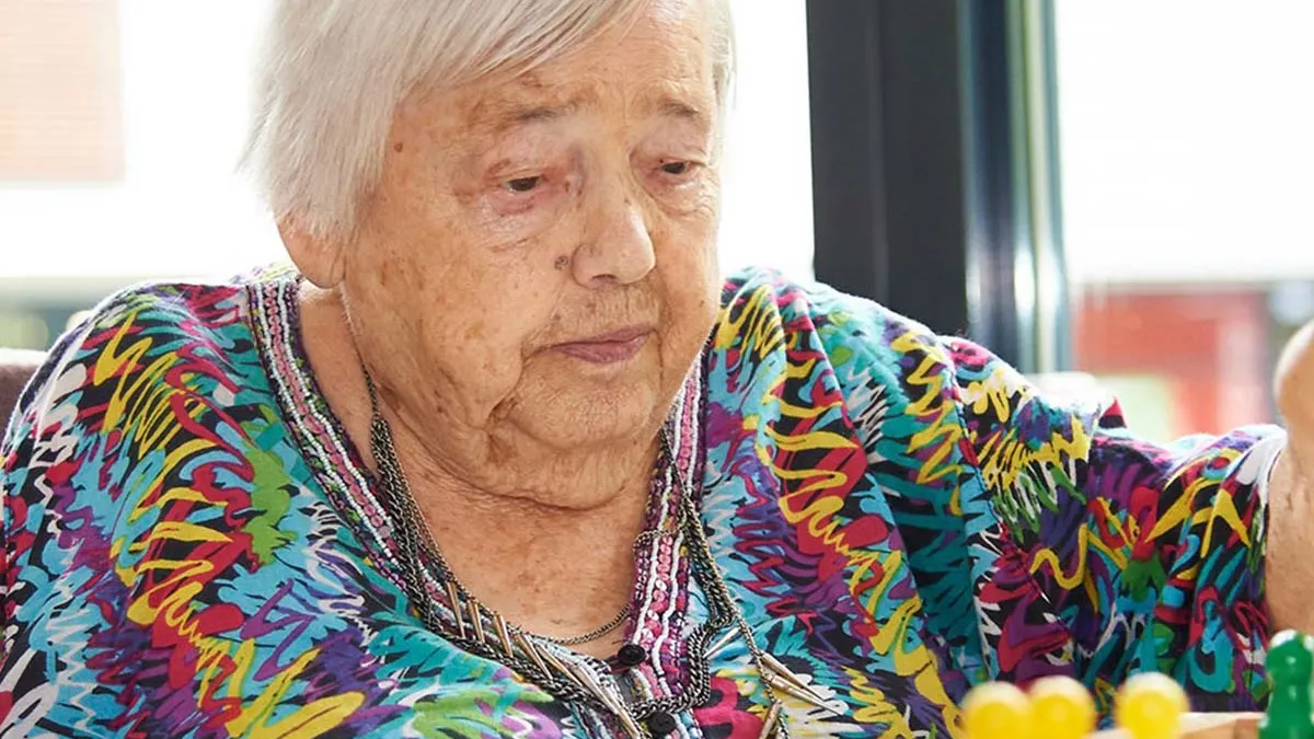 Eine Seniorin beim Spielen von Gesellschaftsspielen während der Freizeit bei PFLEGEN & WOHNEN HAMBURG in Uhlenhorst.