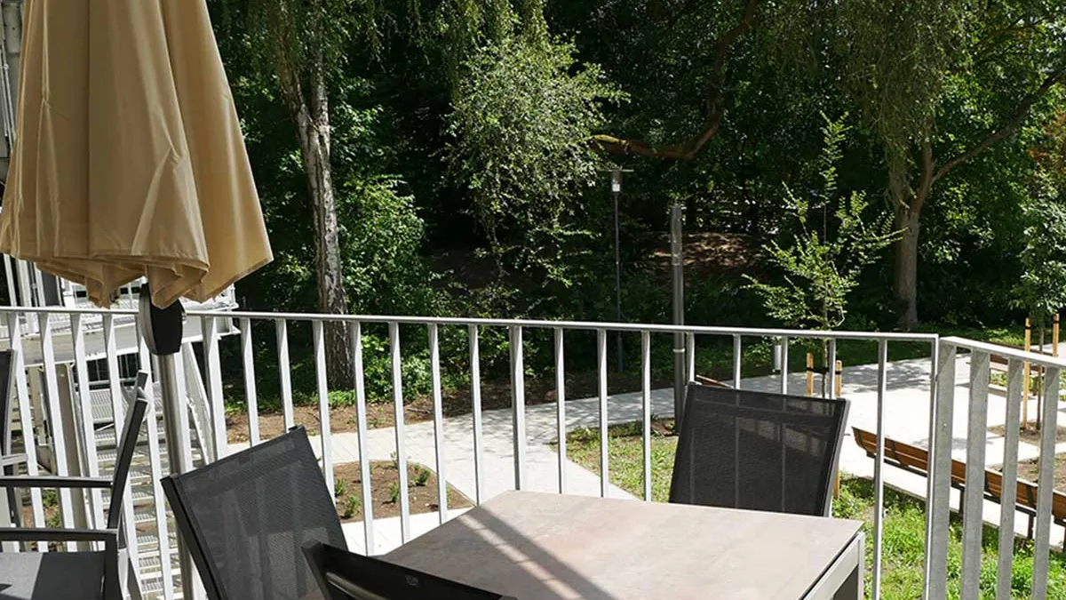 Balkon im PFLEGEN & WOHNEN HAMBURG am Standort Marienthal mit Sonnenschirm, Tisch und Stühlen.